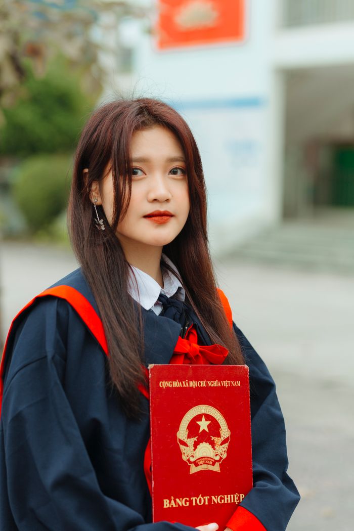 Young woman in graduation attire holding certificate outdoors, symbolizing academic achievement.